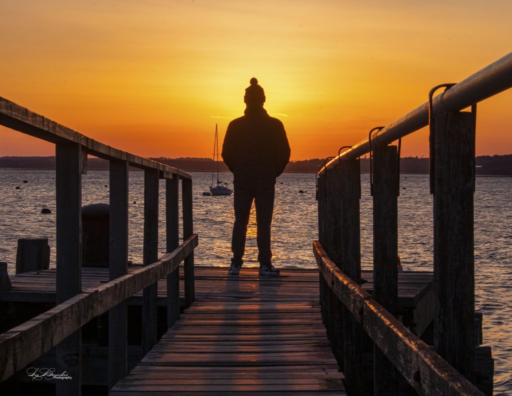 Sunsetting behind man on pier